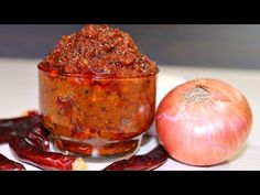 an onion and chili sauce in a small glass bowl next to a red onion on a white surface