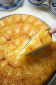 a person cutting into a pineapple upside down cake