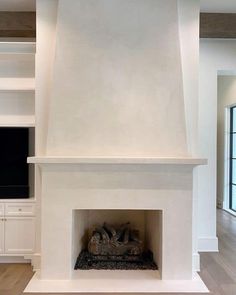 a fireplace in a living room with white walls and wood flooring on the other side