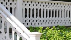 a close up of a white fence and bushes