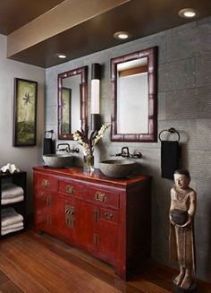 a bathroom with two sinks and mirrors on the wall next to a wooden cabinet in front of it