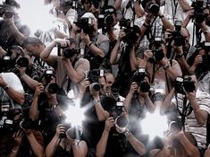 a large group of people taking pictures with their cell phones in front of them and cameras around them