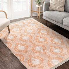 an orange and white rug in a living room next to a gray couch with two chairs