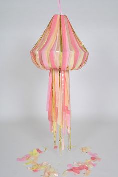 a pink and yellow striped lamp hanging from a ceiling with confetti on the floor