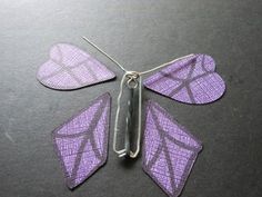 a purple butterfly made out of fabric sitting on top of a black table next to scissors