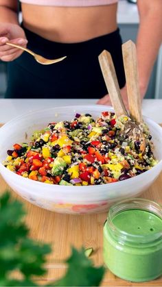 a woman is preparing a colorful salad in a white bowl