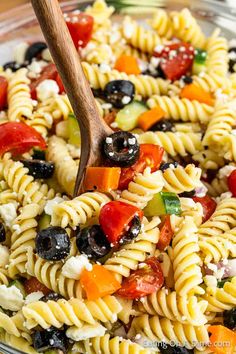 a pasta salad with olives, tomatoes, and feta cheese in a glass bowl