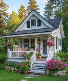 a small white house with flowers on the front porch and steps leading up to it