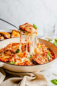 someone is taking a slice of lasagna out of the casserole dish