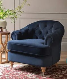 a blue chair sitting on top of a rug next to a vase filled with flowers