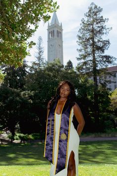 a woman in a graduation gown standing on the grass