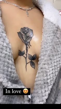 a woman's chest with a rose tattoo on her left side and the words in love written below it