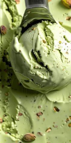 a scoop of ice cream with pistachio and almonds around it on a table