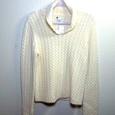 a white sweater hanging on a wall with a hanger in front of the top