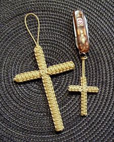 a crocheted cross is next to a lighter