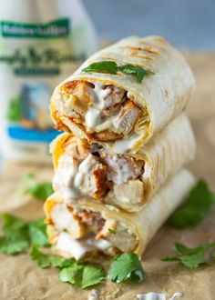 two burritos stacked on top of each other with meat, cheese and cilantro