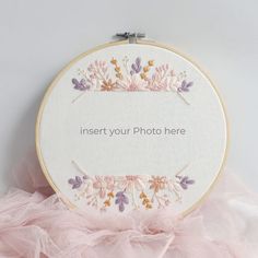 a white embroidered sign with pink and purple flowers on it that says insert your photo here