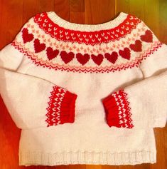 a white sweater with red hearts on it