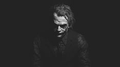 the joker in black and white with his hands on his chest, looking down at something