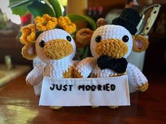 two crocheted stuffed animals sitting next to each other holding a sign that says just married