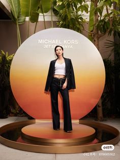 a woman is standing in front of a sign with the name of michael kors