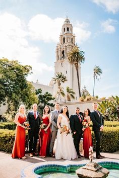 a group of people standing around each other in front of a building with a fountain