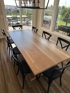 a dining room table with six chairs in front of a large window overlooking the water