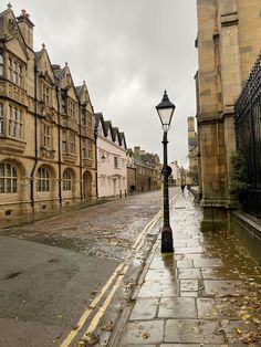 an empty street lined with old buildings and a lamp post in the middle of it