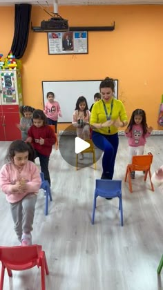 a group of children in a classroom playing with chairs and toys, while an adult watches