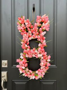 a wreath with pink tulips hanging on the front door