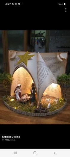 an open book with lights inside it on a wooden table next to a figurine