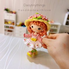 a hand holding a tiny doll on top of a table