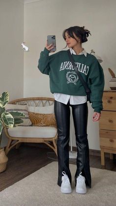 a woman wearing black leather pants and a green sweatshirt