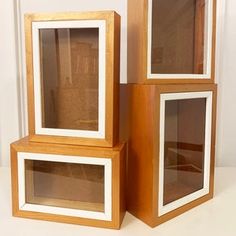 three wood and glass shelves sitting on top of a white table next to each other