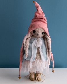 a stuffed animal wearing a pink hat and dress on top of a white table next to a blue wall