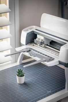 a small potted plant sitting on top of a cutting board next to a machine