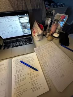 an open laptop computer sitting on top of a desk next to a notebook and calculator