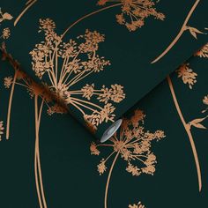 a green and gold wallpaper with floral designs on the side, along with a metal spoon