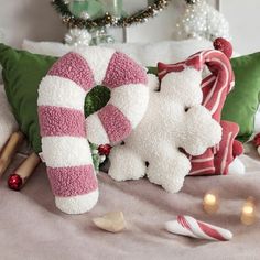 two white teddy bears sitting on top of a bed next to candy canes and christmas decorations