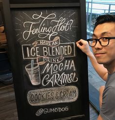 a man standing next to a chalk board sign