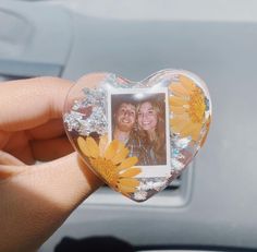 a person holding up a heart shaped photo frame with flowers on the front and back