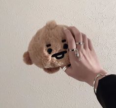 a person holding a teddy bear up to their face with rings on it's fingers