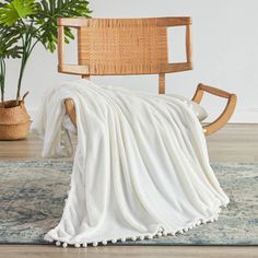 a chair with a blanket on top of it in front of a potted plant