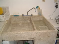 a sink that is made out of concrete in a room with other items on the floor