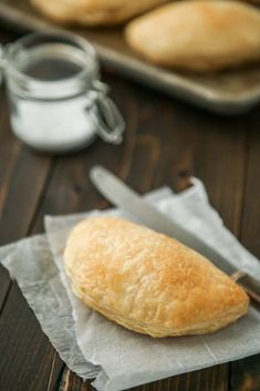 a piece of bread sitting on top of a piece of wax paper next to a knife