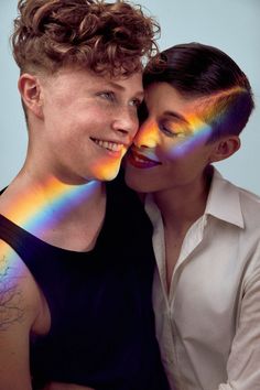 two people with their faces painted like rainbows and one is hugging the other's head