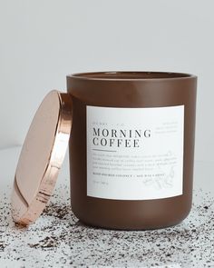 a candle sitting on top of a white table next to a container with a brown lid