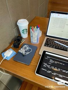 an open laptop computer sitting on top of a wooden desk next to a cup of coffee