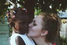 a woman kissing a small child on the cheek