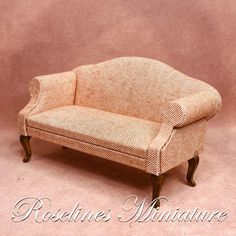 a small couch sitting on top of a pink floor next to a wooden frame chair